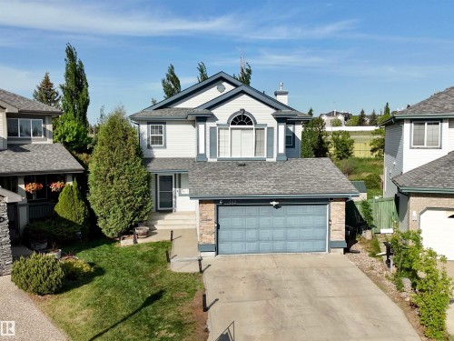 Two-story residence featuring light-toned siding, a dark blue garage door, and a stone facade accent - 442 Hunters Green, Edmonton, AB - Outdoor