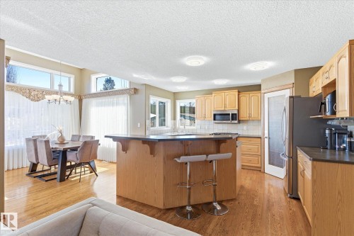 Open-concept kitchen and dining area featuring wood-finish flooring, light wood cabinetry, and recessed lighting - 442 Hunters Green, Edmonton, AB - Indoor Photo Showing Kitchen