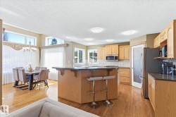 Open-concept kitchen and dining area featuring wood-finish flooring, light wood cabinetry, and recessed lighting - 
