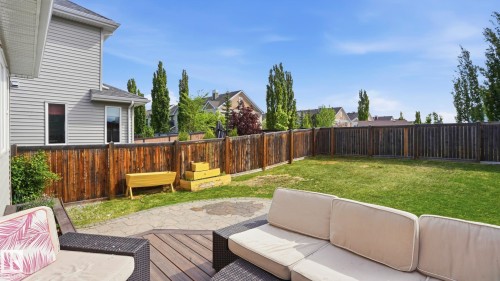 Expansive backyard featuring a manicured lawn, a full-height privacy fence, a wood-finish deck, and a paver patio area - 1915 77 Street, Edmonton, AB - Outdoor With Deck Patio Veranda