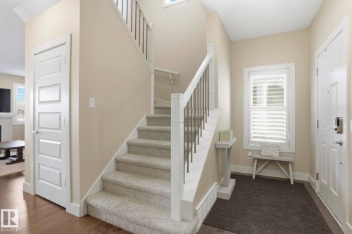Staircase with light-toned carpeted treads, white risers, and dark metal balusters - 1915 77 Street, Edmonton, AB - Indoor Photo Showing Other Room