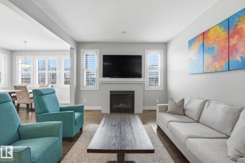 Living area with a fireplace, wood-finish flooring, and white plantation shutters - 1915 77 Street, Edmonton, AB - Indoor Photo Showing Living Room With Fireplace