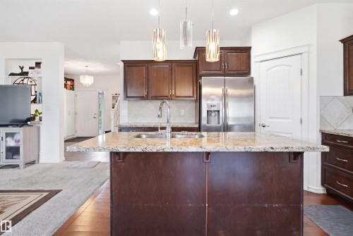 Kitchen featuring a substantial island with a composite stone countertop, an undermount sink, and a gooseneck faucet - 1523 36 Avenue, Edmonton, AB - Indoor Photo Showing Kitchen With Double Sink With Upgraded Kitchen