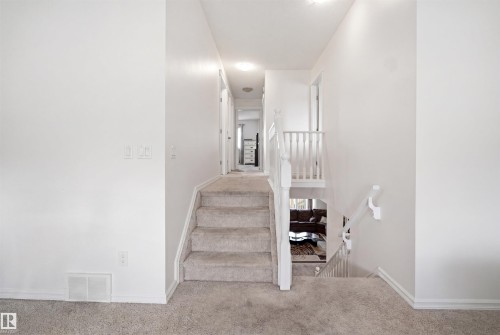 Central staircase with light grey carpeted treads and white painted risers - 1523 36 Avenue, Edmonton, AB - Indoor Photo Showing Other Room