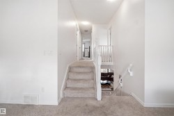 Central staircase with light grey carpeted treads and white painted risers - 