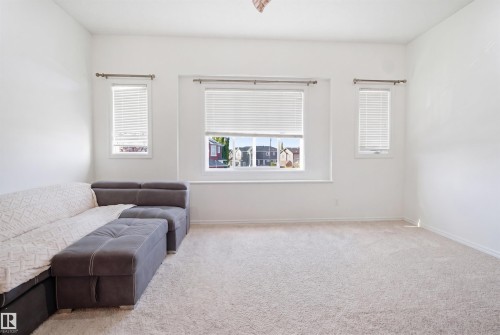 Spacious room featuring light-toned carpet flooring, white walls, and multiple windows with horizontal blinds - 1523 36 Avenue, Edmonton, AB - Indoor