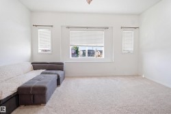 Spacious room featuring light-toned carpet flooring, white walls, and multiple windows with horizontal blinds - 