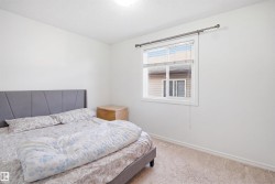 Bright room featuring neutral carpeting, white walls, a single window with blinds, and white baseboards - 