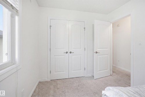 Interior room featuring a double-door closet with satin nickel hardware, a single window with blinds, and light-toned carpeting - 1523 36 Avenue, Edmonton, AB - Indoor Photo Showing Bedroom