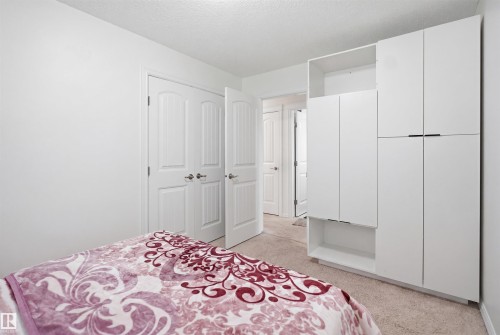 White bedroom featuring built-in wardrobe cabinetry with matte black pulls, neutral carpet, and two-panel interior doors - 1523 36 Avenue, Edmonton, AB - Indoor Photo Showing Bedroom