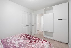 White bedroom featuring built-in wardrobe cabinetry with matte black pulls, neutral carpet, and two-panel interior doors - 