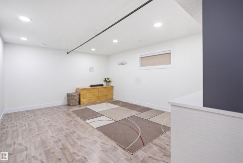 Spacious room featuring light wood-finish flooring, recessed ceiling lighting, a built-in window, and white baseboards - 1523 36 Avenue, Edmonton, AB - Indoor Photo Showing Other Room
