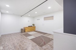 Spacious room featuring light wood-finish flooring, recessed ceiling lighting, a built-in window, and white baseboards - 