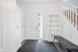 Entryway featuring bright white walls, wood-finish flooring, and a traditional white paneled door with sidelight - 