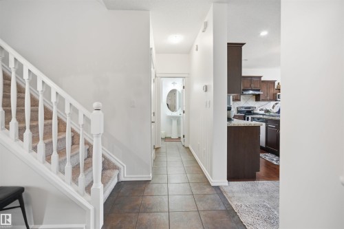 Entryway featuring neutral-toned tile flooring, a carpeted staircase with white balusters, and recessed lighting - 1523 36 Avenue, Edmonton, AB - Indoor Photo Showing Other Room
