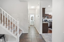Entryway featuring neutral-toned tile flooring, a carpeted staircase with white balusters, and recessed lighting - 