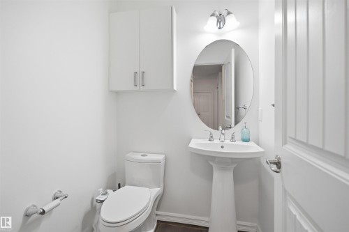 Pedestal sink with an oval mirror and wall-mounted vanity light - 1523 36 Avenue, Edmonton, AB - Indoor Photo Showing Bathroom