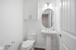 Pedestal sink with an oval mirror and wall-mounted vanity light - 