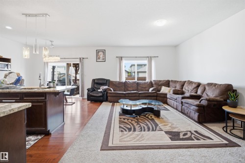 Open-concept living area featuring a kitchen island with stone countertop, dark wood-finish cabinetry, and wood-finish flooring - 1523 36 Avenue, Edmonton, AB - Indoor Photo Showing Living Room