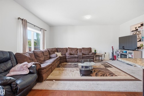 Spacious living area featuring light-toned walls, wood-finish flooring, and a large window providing natural light - 1523 36 Avenue, Edmonton, AB - Indoor Photo Showing Living Room