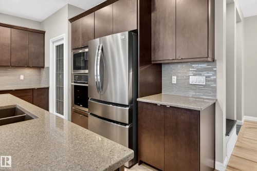 Modern kitchen featuring dark wood cabinetry and a stainless steel refrigerator - 17838 60A Street, Edmonton, AB - Indoor Photo Showing Kitchen With Double Sink With Upgraded Kitchen