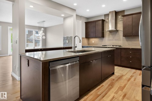 Kitchen featuring a large central island with an undermount sink, stainless steel dishwasher, stone countertop, and recessed lighting - 17838 60A Street, Edmonton, AB - Indoor Photo Showing Kitchen With Double Sink With Upgraded Kitchen