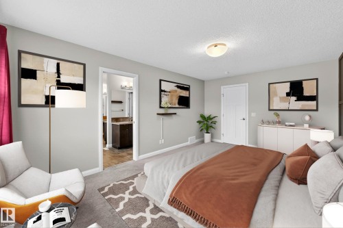 Carpeted bedroom with a recessed doorway leading to a bathroom featuring a vanity with a stone-finish countertop - 17838 60A Street, Edmonton, AB - Indoor Photo Showing Bedroom