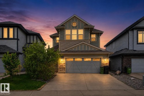 Front exterior featuring an attached double-car garage, stone accents, horizontal siding, and a gabled roofline - 17838 60A Street, Edmonton, AB - Outdoor With Facade