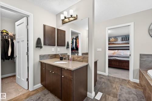 Bathroom vanity featuring a light-toned countertop, integrated sink, dark wood-finish cabinetry, and a large mirror - 17838 60A Street, Edmonton, AB - Indoor Photo Showing Bathroom