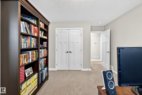 Built-in bookcase with crown molding, paneled interior doors, light neutral wall color, and textured ceiling - 17838 60A Street, Edmonton, AB - Indoor