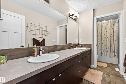 Dual vanity with integrated sinks, stone-finish countertop, and dark wood cabinetry - 17838 60A Street, Edmonton, AB - Indoor Photo Showing Bathroom