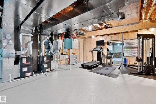 Unfinished basement featuring exposed wood beams, concrete flooring, and extensive HVAC ductwork - 17838 60A Street, Edmonton, AB - Indoor Photo Showing Gym Room
