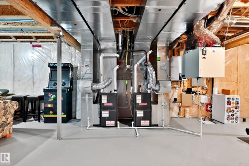 Basement utility area featuring two furnaces, exposed ductwork, and open ceiling joists - 17838 60A Street, Edmonton, AB - Indoor Photo Showing Basement