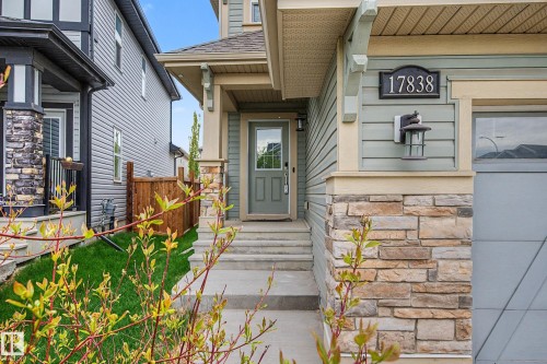 Exterior entry featuring stacked stone accents, horizontal siding, a covered porch, and a light-paneled front door - 17838 60A Street, Edmonton, AB - Outdoor