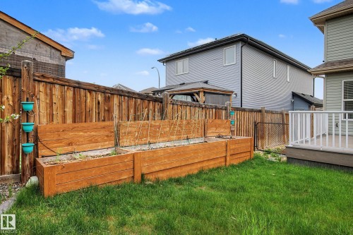 Fenced backyard featuring a manicured lawn, two built-in raised garden beds, and a composite material deck with white railings - 17838 60A Street, Edmonton, AB - Outdoor With Deck Patio Veranda With Exterior