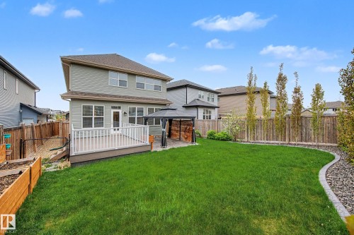 Expansive backyard featuring a large composite deck with white railings, a paved patio with a gazebo, a manicured lawn, and a wooden privacy fence with mature trees - 17838 60A Street, Edmonton, AB - Outdoor With Deck Patio Veranda