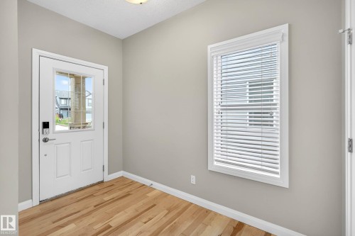 Entryway featuring a white paneled door with integrated glass, wood-finish flooring, and light gray wall paint - 17838 60A Street, Edmonton, AB - Indoor Photo Showing Other Room