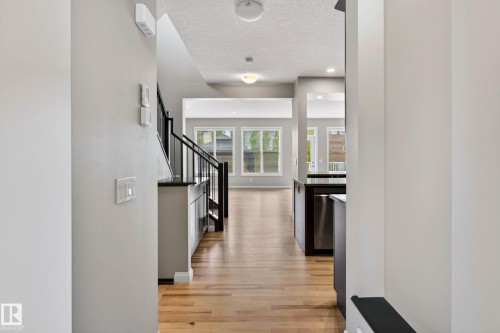 Expansive interior featuring wood-finish flooring, a contemporary staircase with black metal railings, recessed lighting, large windows, and a built-in kitchen island with stainless steel appliances - 17838 60A Street, Edmonton, AB - Indoor Photo Showing Other Room