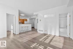 Spacious living area featuring wood-finish flooring, white walls, and a glass block transom window - 