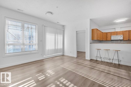 Open-concept living area featuring wood-finish flooring, white walls, and recessed lighting - 117 10717 83 Avenue, Edmonton, AB - Indoor