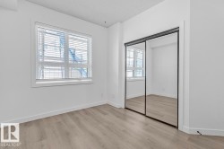 Bright room featuring wood-finish flooring, a large window with horizontal blinds, and a mirrored sliding closet door - 