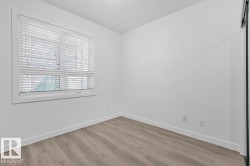 Room featuring wood-finish flooring, white baseboards, and a window with blinds - 