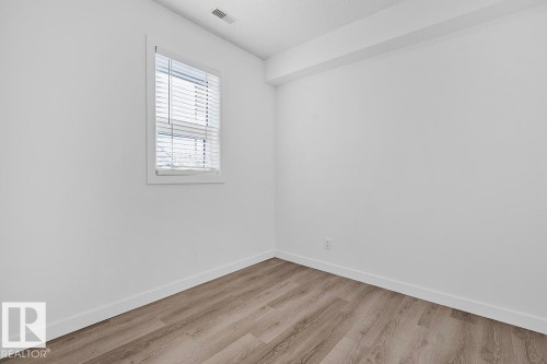 Room featuring light wood-finish flooring, white walls, and a window with white blinds - 117 10717 83 Avenue, Edmonton, AB - Indoor Photo Showing Other Room