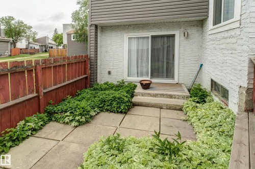 Patio space with concrete paver flooring, perimeter landscaping, and wooden privacy fencing - 5626 19A Avenue, Edmonton, AB 
