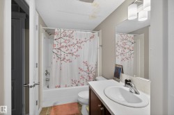 Bathroom featuring a combined tub and shower, a single vanity with a white countertop, and a large wall-mounted mirror - 