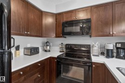 Kitchen featuring wood-finish cabinetry, white countertops, black appliances, and a black built-in microwave - 