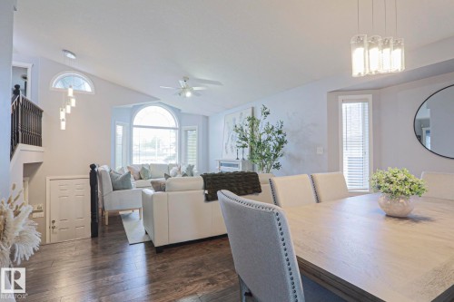 Open-concept living and dining areas featuring wood-finish flooring, vaulted ceilings, and large arched windows - 313 Jillings Crescent, Edmonton, AB - Indoor Photo Showing Other Room