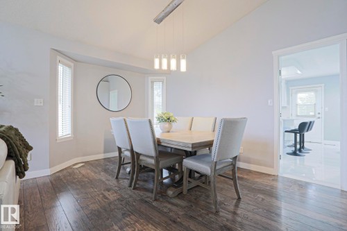 Dining area with vaulted ceilings, wood-finish flooring, and a contemporary chandelier - 313 Jillings Crescent, Edmonton, AB - Indoor Photo Showing Dining Room