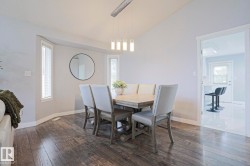 Dining area with vaulted ceilings, wood-finish flooring, and a contemporary chandelier - 