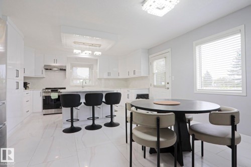 Modern kitchen featuring white cabinetry, a central island with seating, stainless steel appliances, and a tiled backsplash - 313 Jillings Crescent, Edmonton, AB - Indoor
